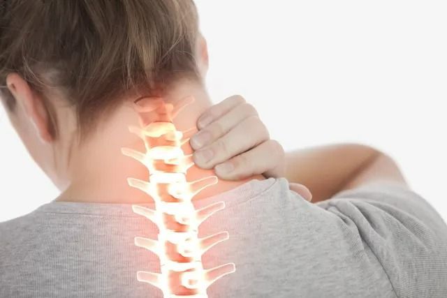 A person holding their neck in pain with an illustration of the cervical spine highlighted in glowing light.