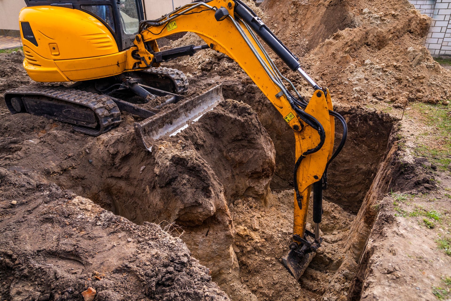 A large yellow excavator is digging a hole in the ground.