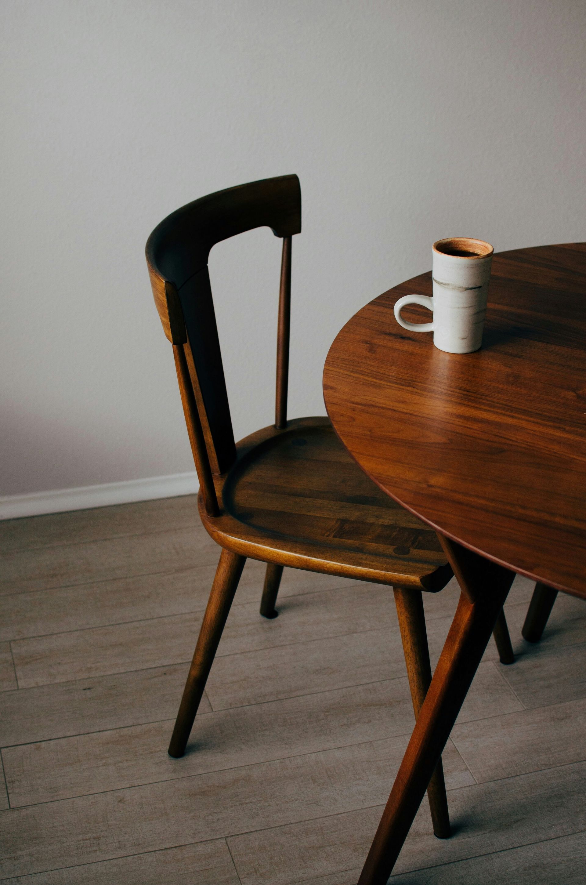 chair tucked under table with coffee cup atop table