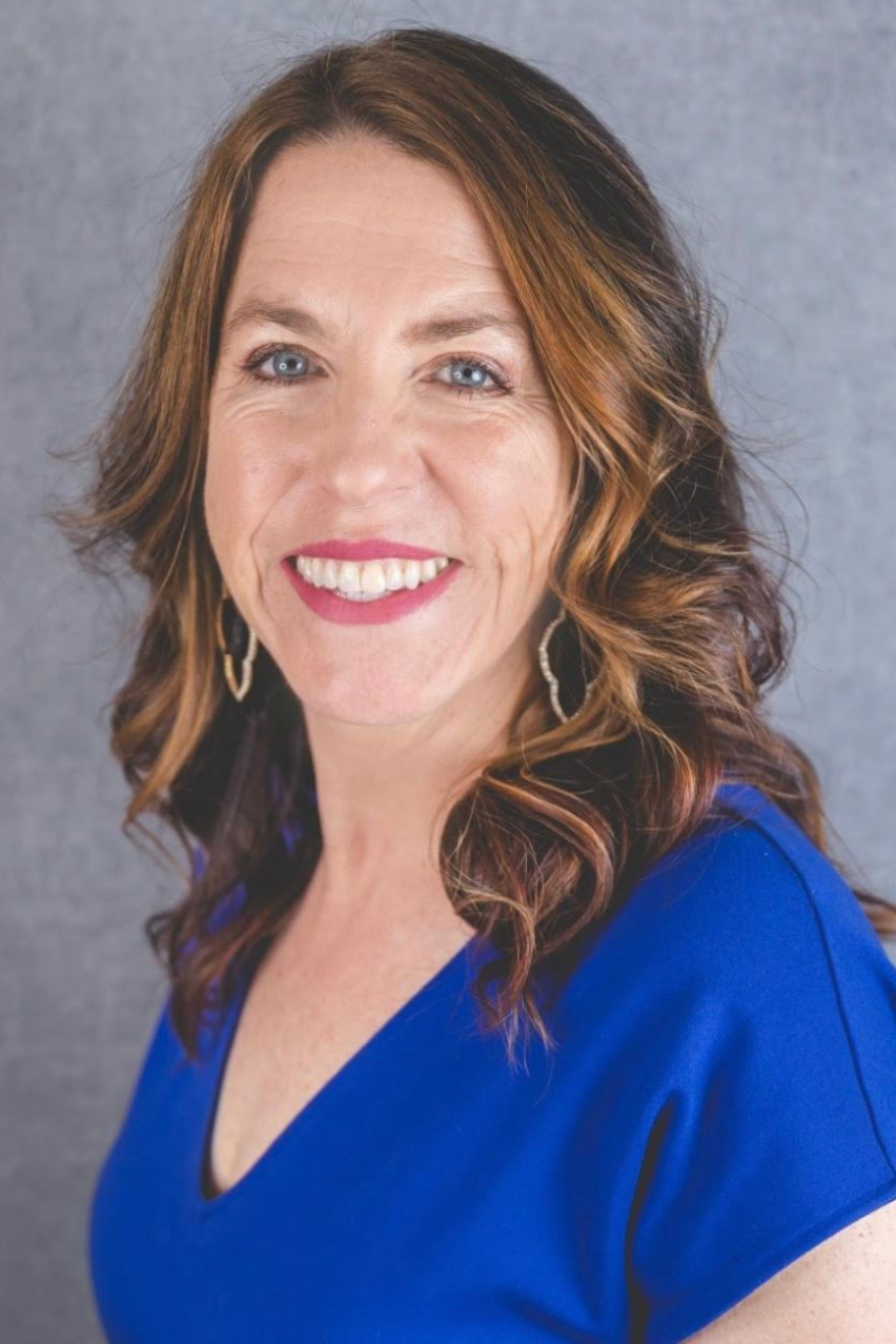 Smiling woman in a blue dress against a gray studio backdrop