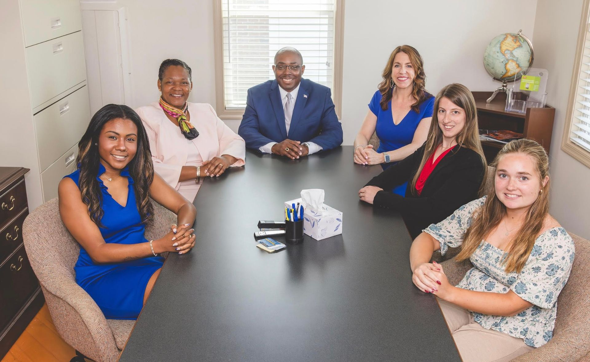 Six people seated around a conference table in a meeting room, facing the camera.