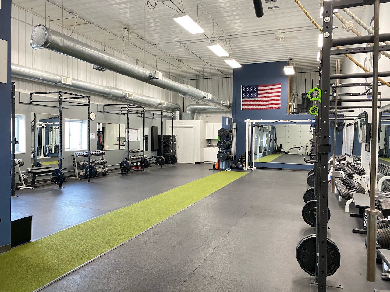 A large gym with a lot of equipment and a flag on the wall.