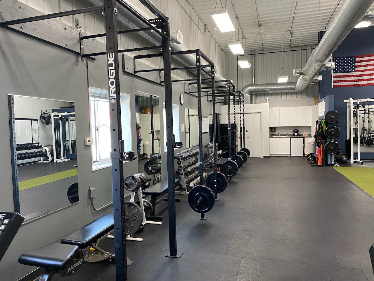 A gym filled with lots of exercise equipment and an american flag.
