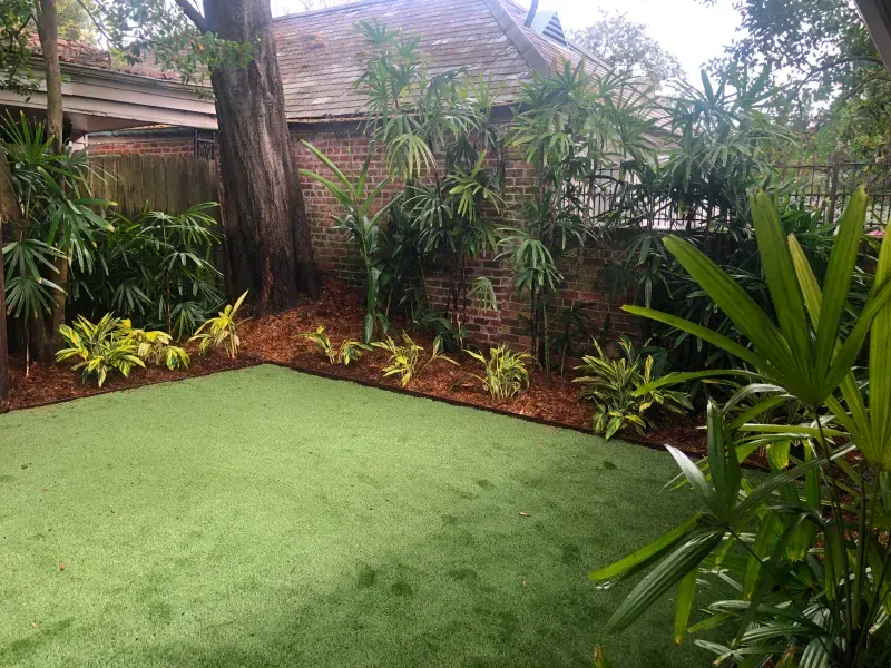 A backyard with a lush green lawn surrounded by trees and bushes.