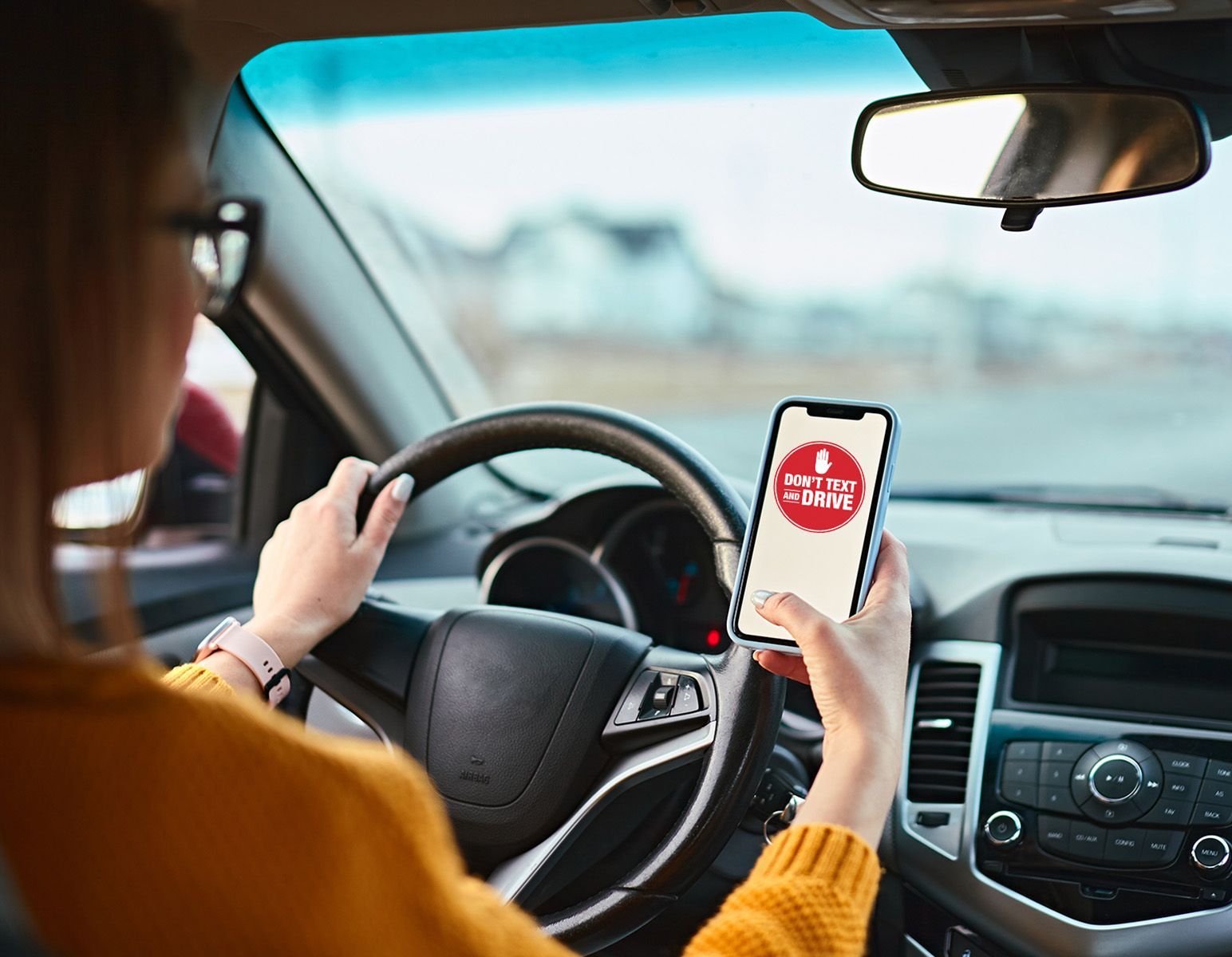 Female driver looking at her phone while driving