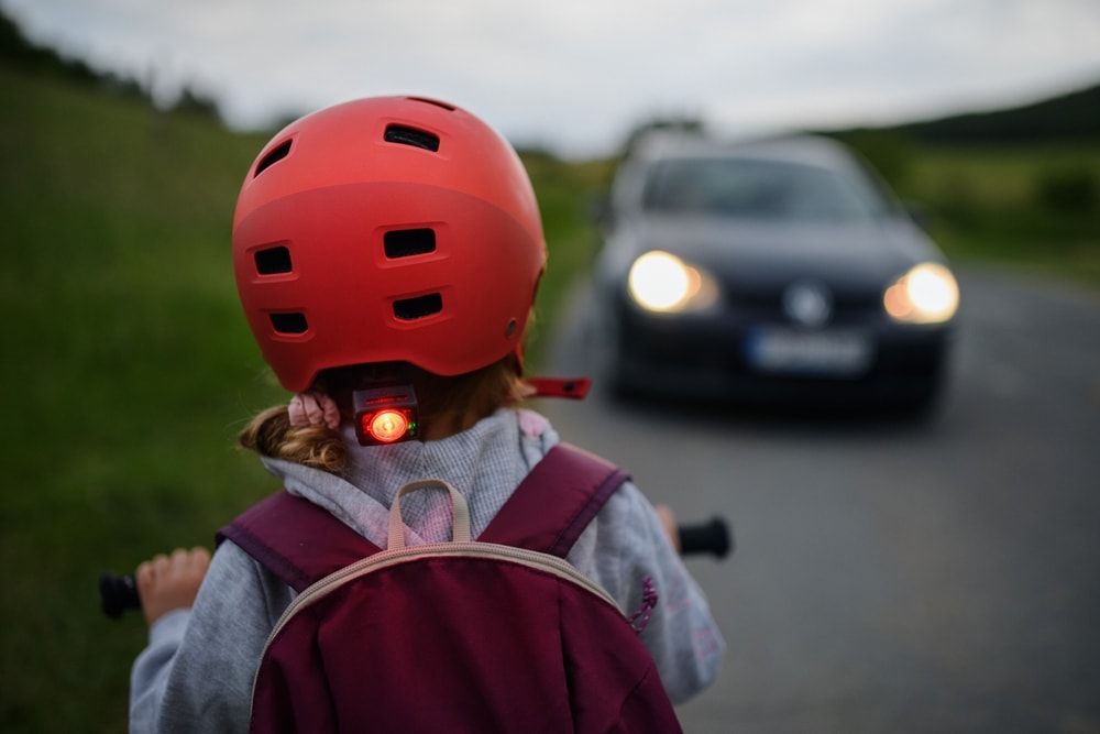 child riding e-bike near cars