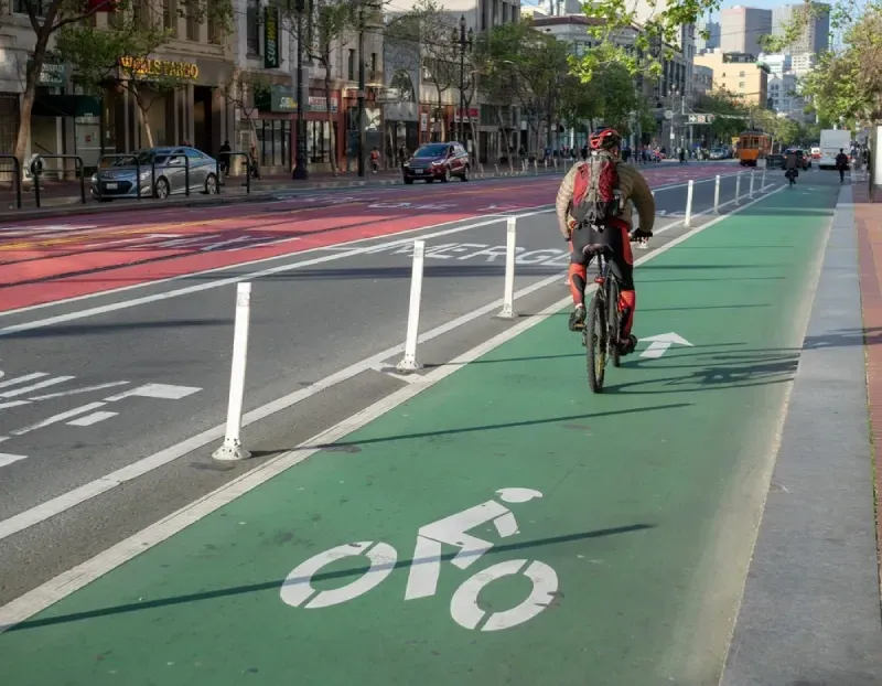 Cyclist riding on a protected bike lane with green paint and bollards in San Francisco