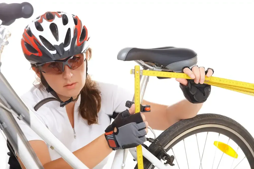 female cyclist with tape measure adjusting the seat height on her bicycle