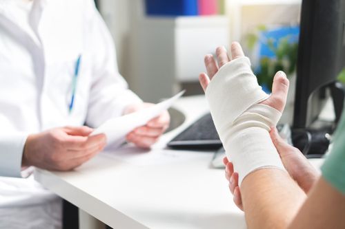 man holding injured hand wrapped in medical tape with doctor