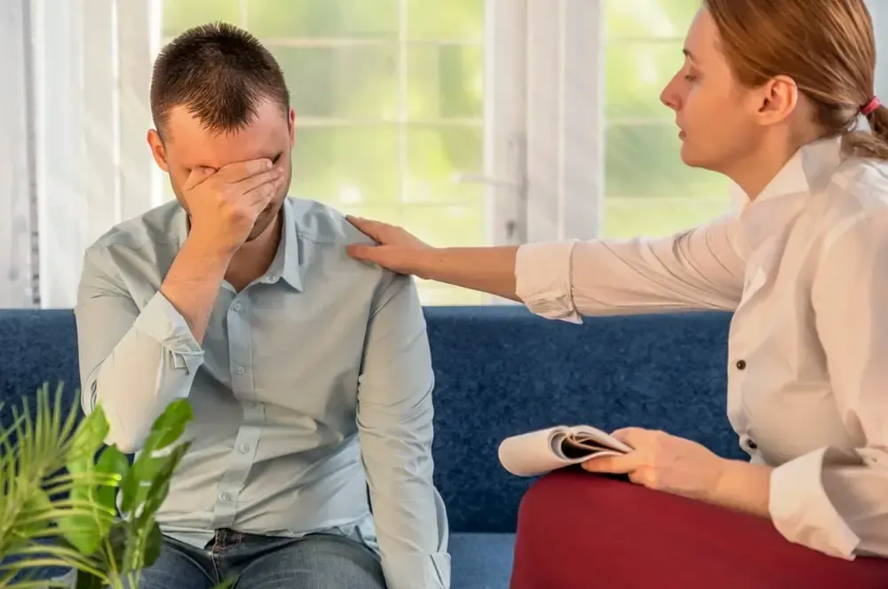 man being consoled by female therapist