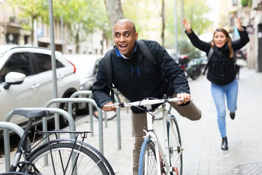 Man stealing a bicycle from a woman who is chasing after him