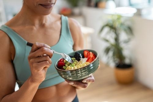 Nutrition and hydration. Athletic woman eating bowl of yogurt and fruit