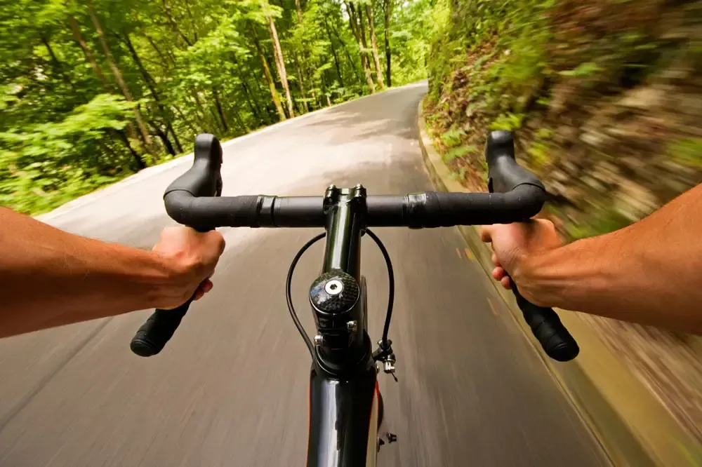 Road bike with riders hands in the drops of the bars