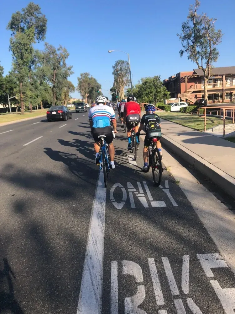 Southern California road with a painted bike lane and a group of cyclclists riding in it near traffic.