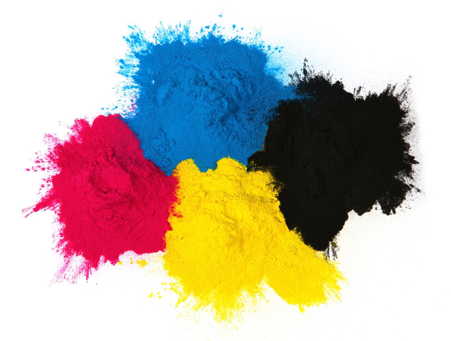 Mucchi di polvere ciano, magenta, gialla e nera, che rappresentano il modello di colore CMYK, su uno sfondo bianco.