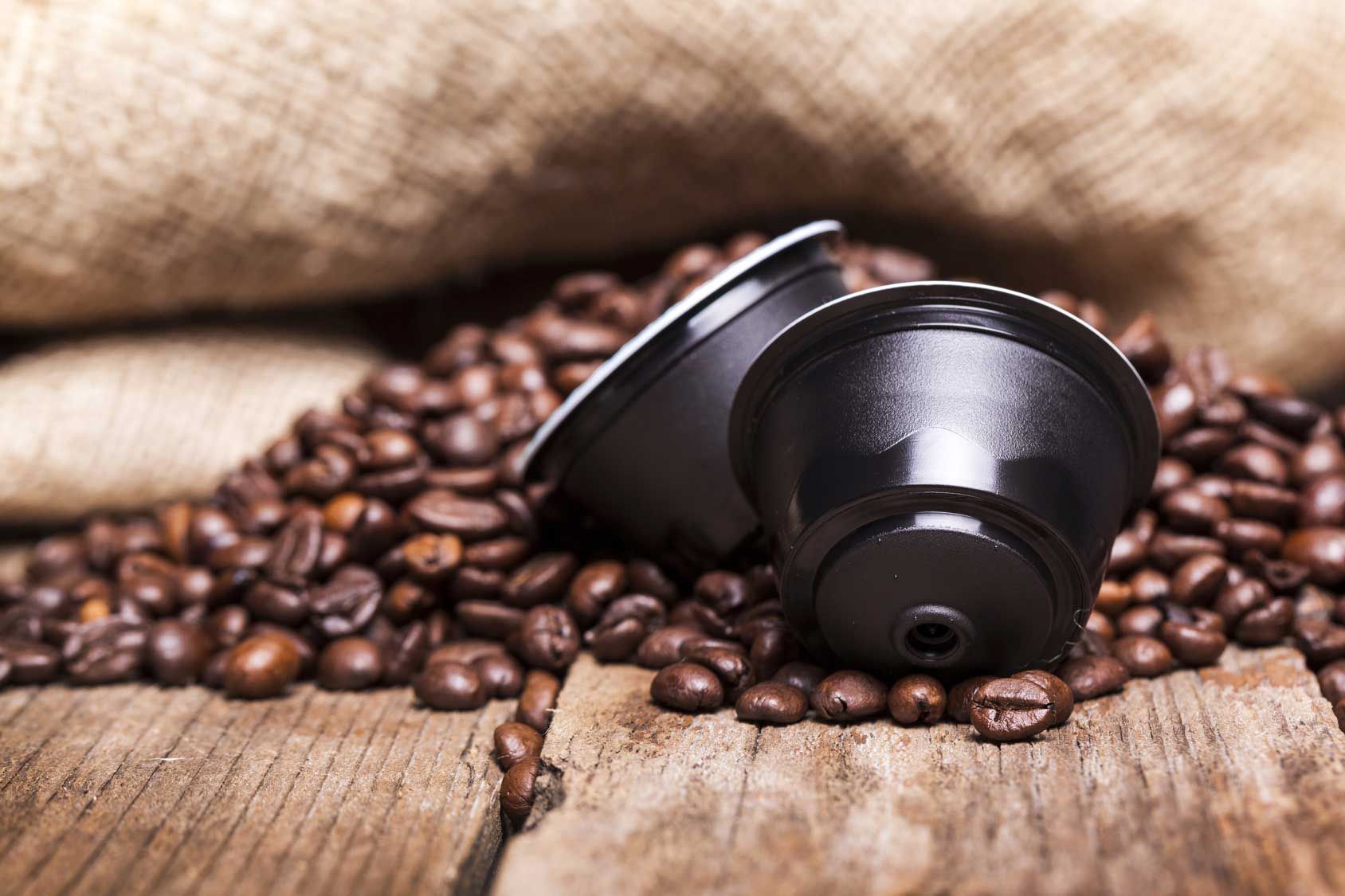 Cialda di caffè e bustina di alluminio. Confezione argentata con caffè scuro all'interno di una cialda trasparente.