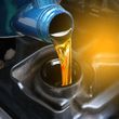 Motor oil pouring from a blue bottle into an engine oil filler opening