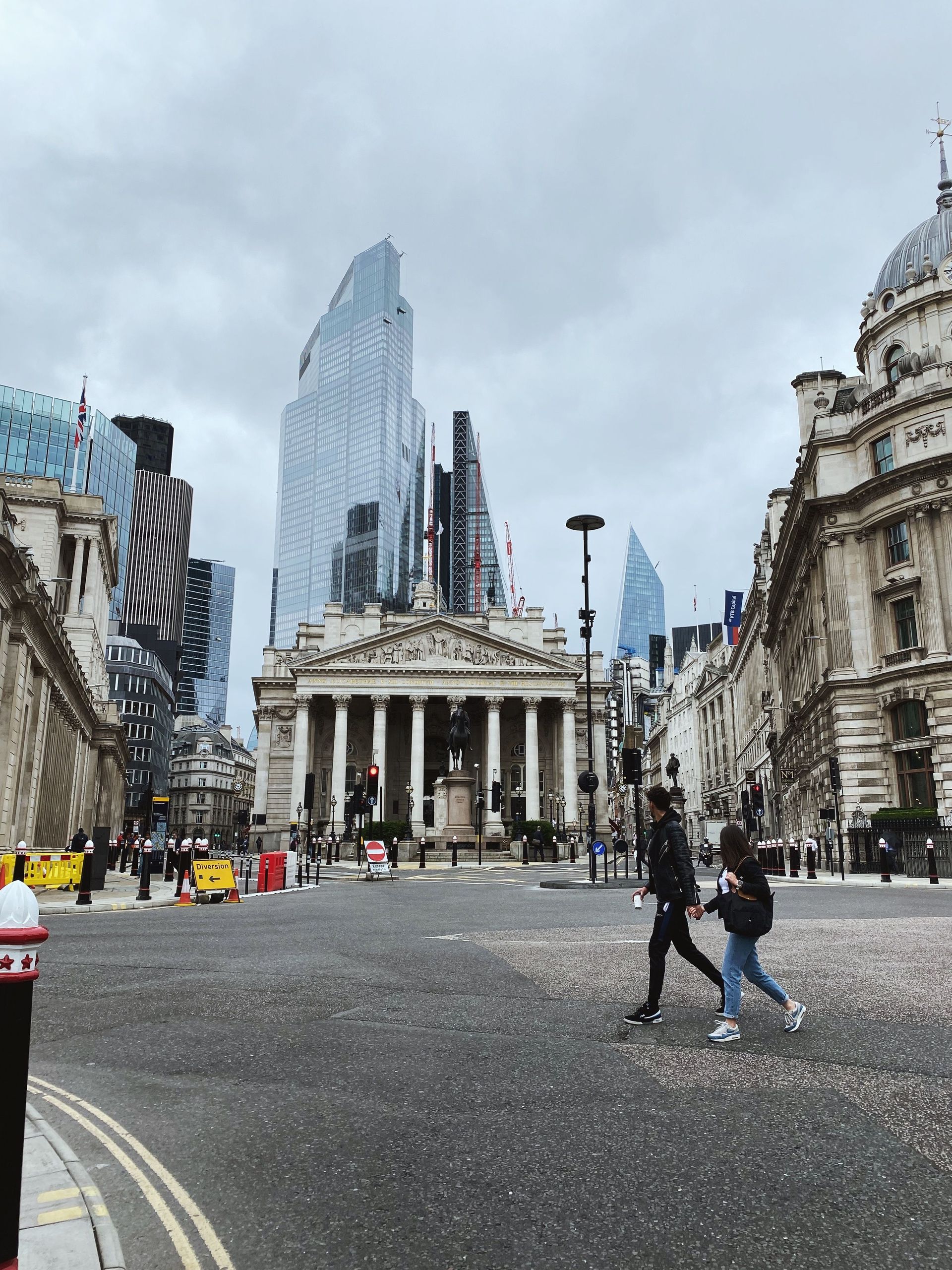 City square with a historic building, modern skyscrapers, and people crossing a confetti-covered street.