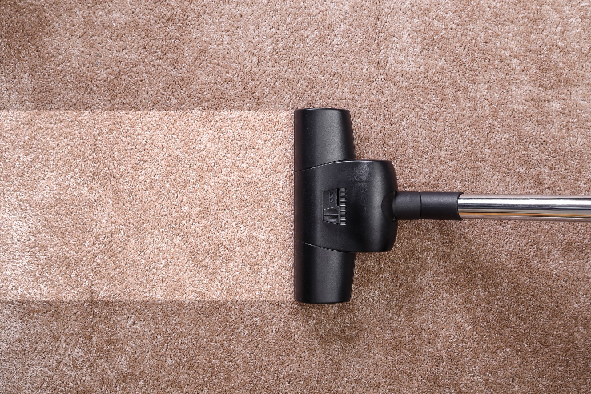 A vacuum cleaner is being used to clean a carpet.