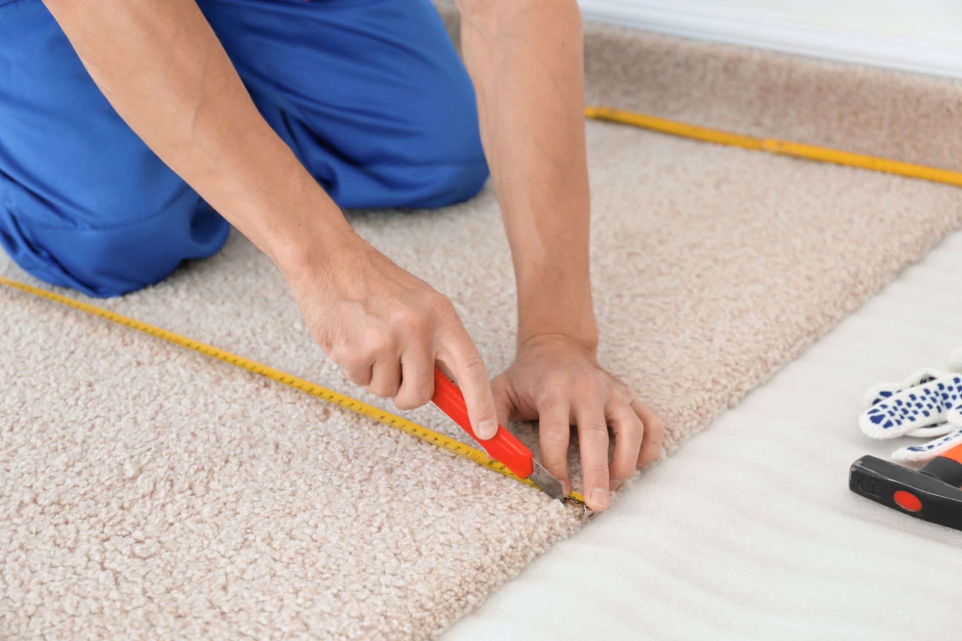 A man is measuring a piece of carpet with a tape measure.
