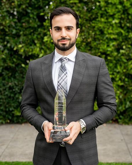 A man in a suit and tie is holding a trophy.
