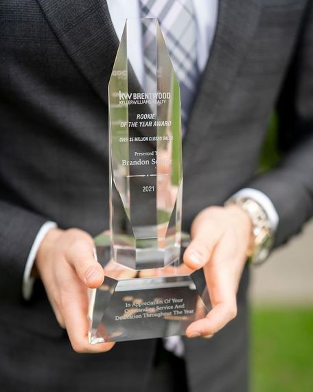 A man in a suit and tie is holding a trophy