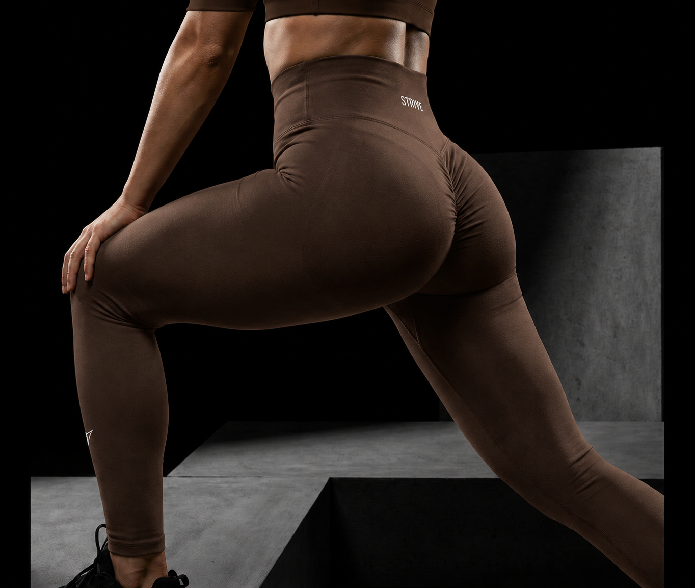 Person stretching in brown leggings on a dark studio set