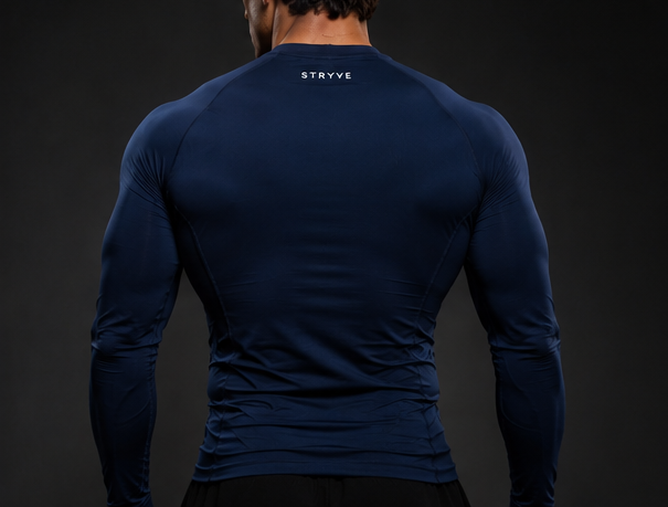 Man in navy athletic shirt and black pants posing against a dark background