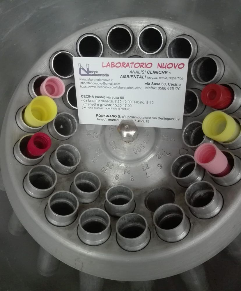 Vista dall'alto di un contenitore rotondo con tappi colorati attorno a un'etichetta centrale di laboratorio.