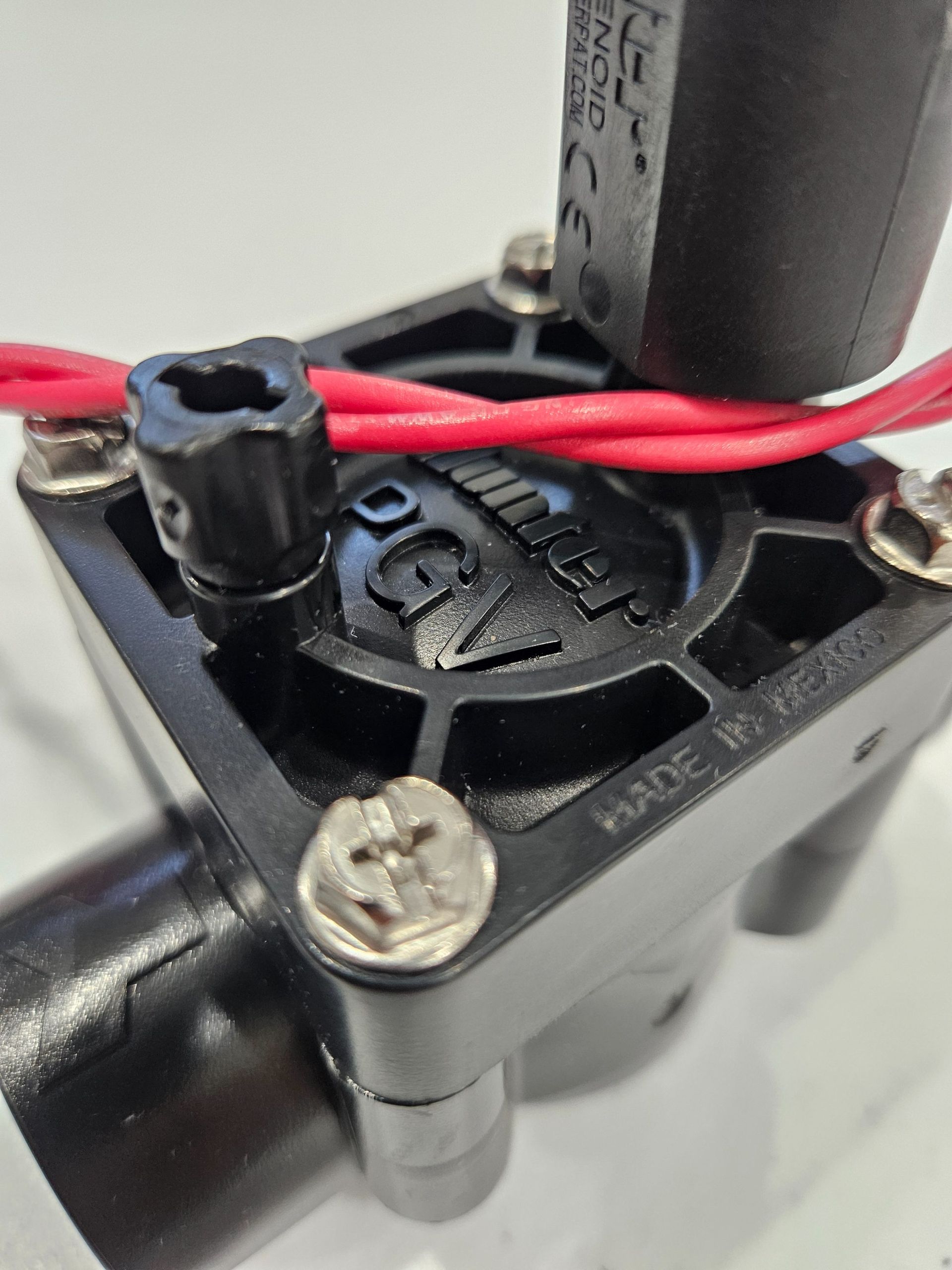 Close-up of a small black fan with red wires and silver screws on a device frame