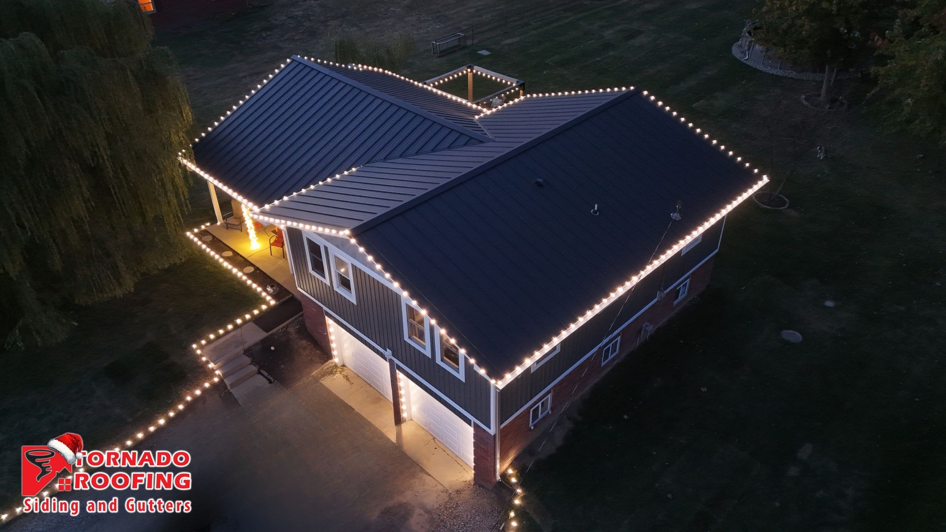 House decorated with white Christmas lights on the roof and around the driveway.