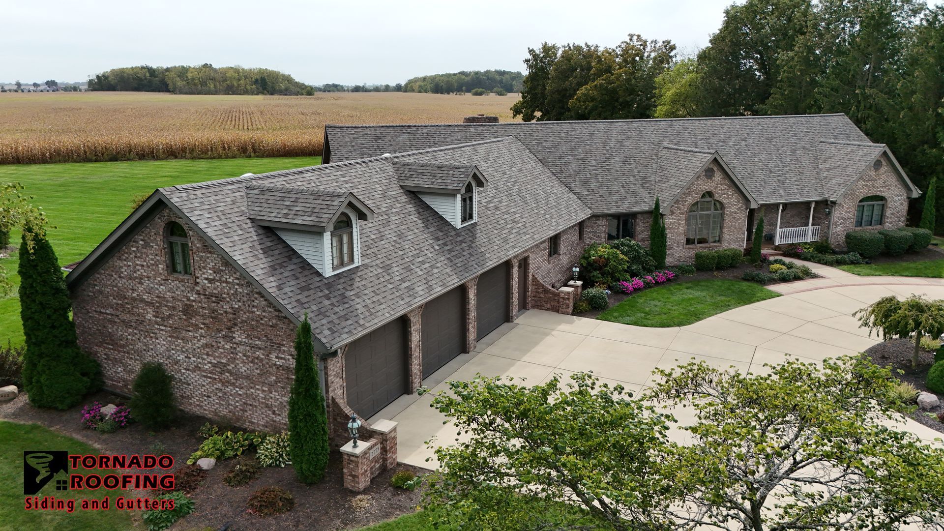 Roof with gray shingles, brick chimney, and trees with sunlight.