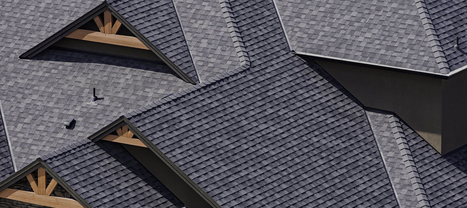 Overhead view of a gray shingled roof with wooden triangle supports.