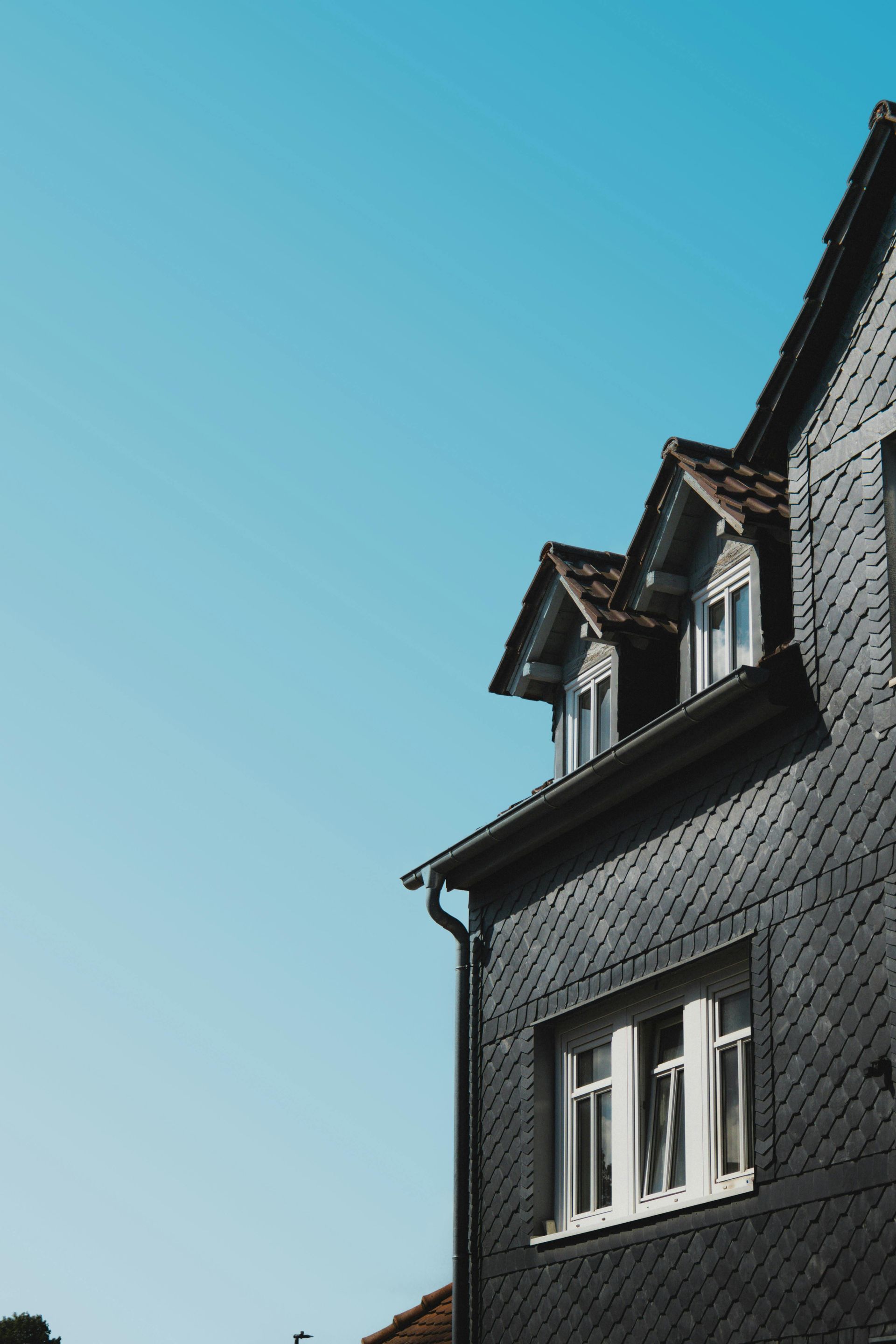 Dark gray building with white-framed windows against a bright blue sky.