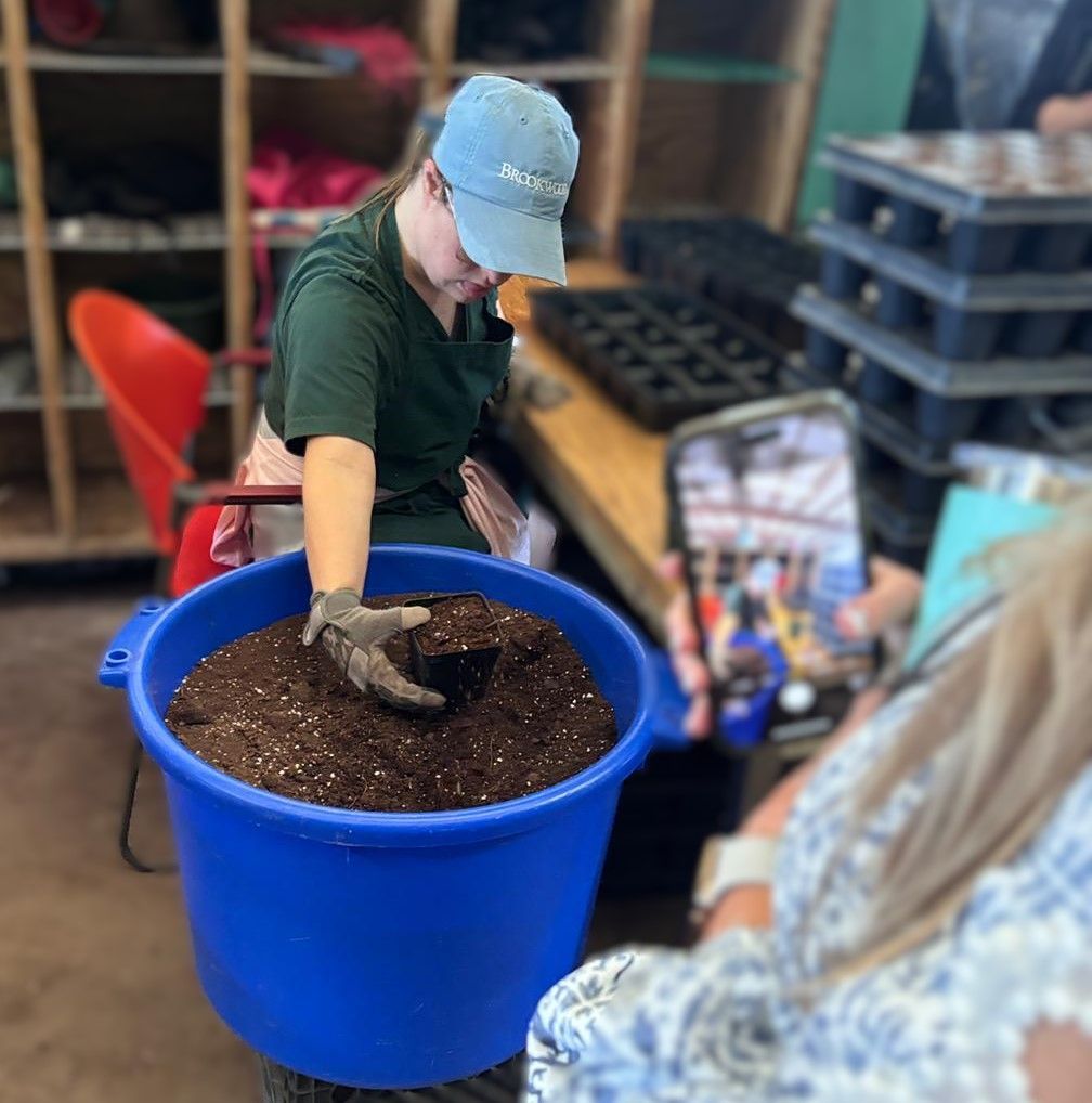 A person is holding a blue bucket filled with dirt.