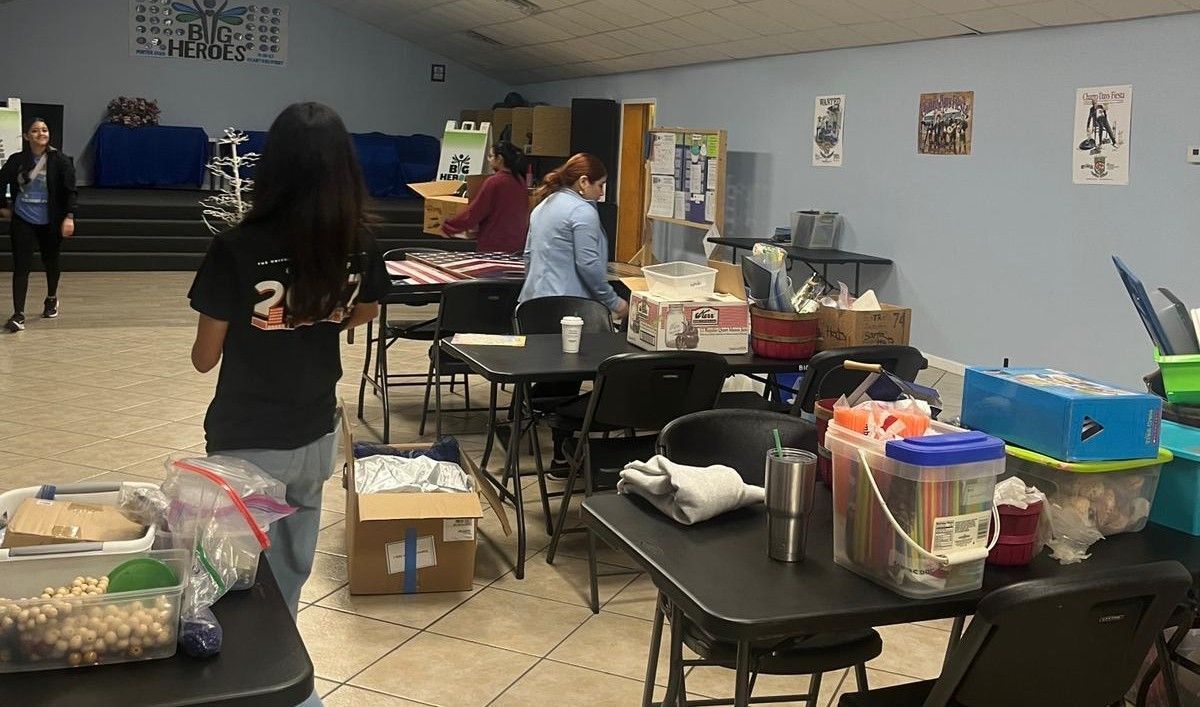 People sorting items at tables in a room; boxes and supplies are visible.