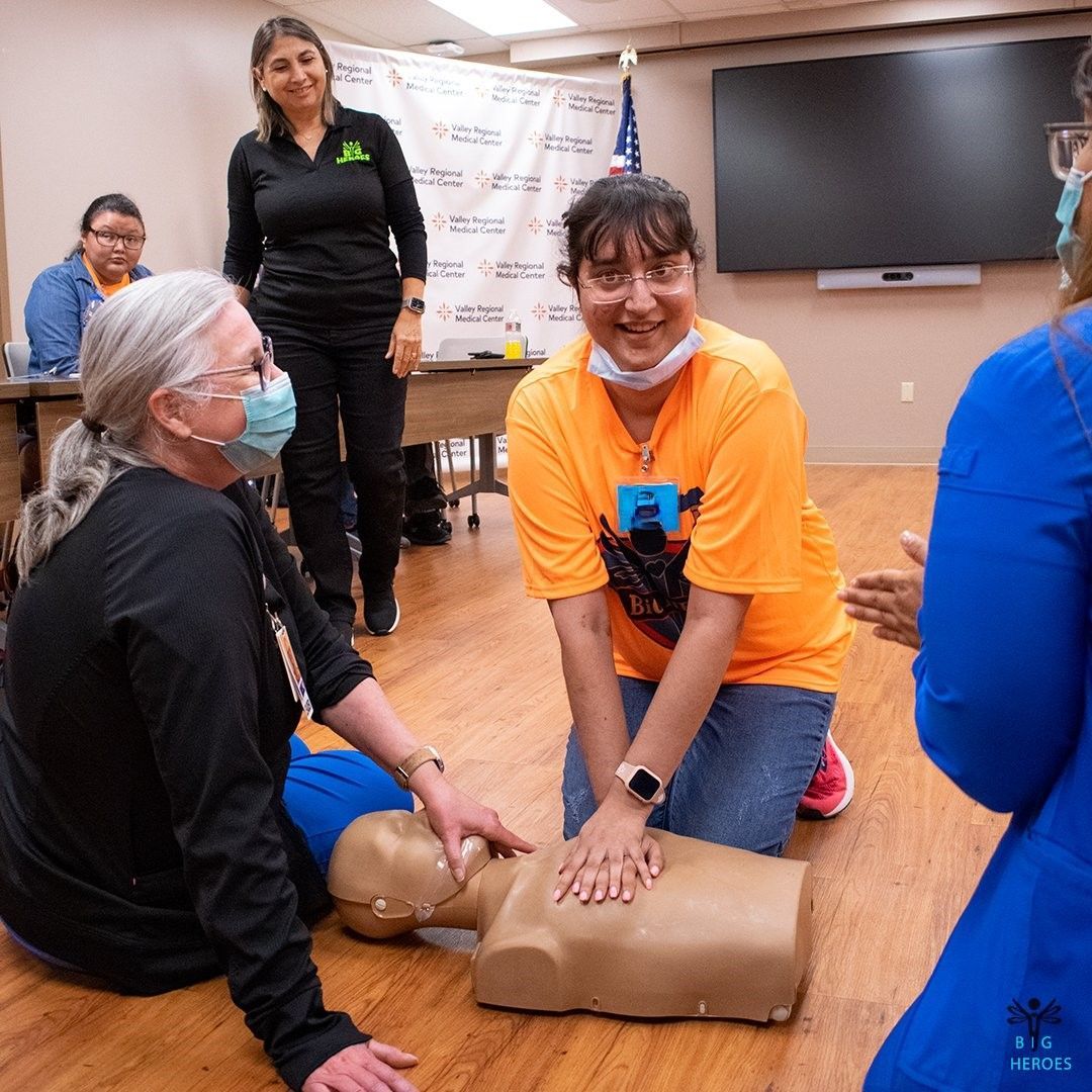 A group of women are sitting on the floor with a mannequin.
