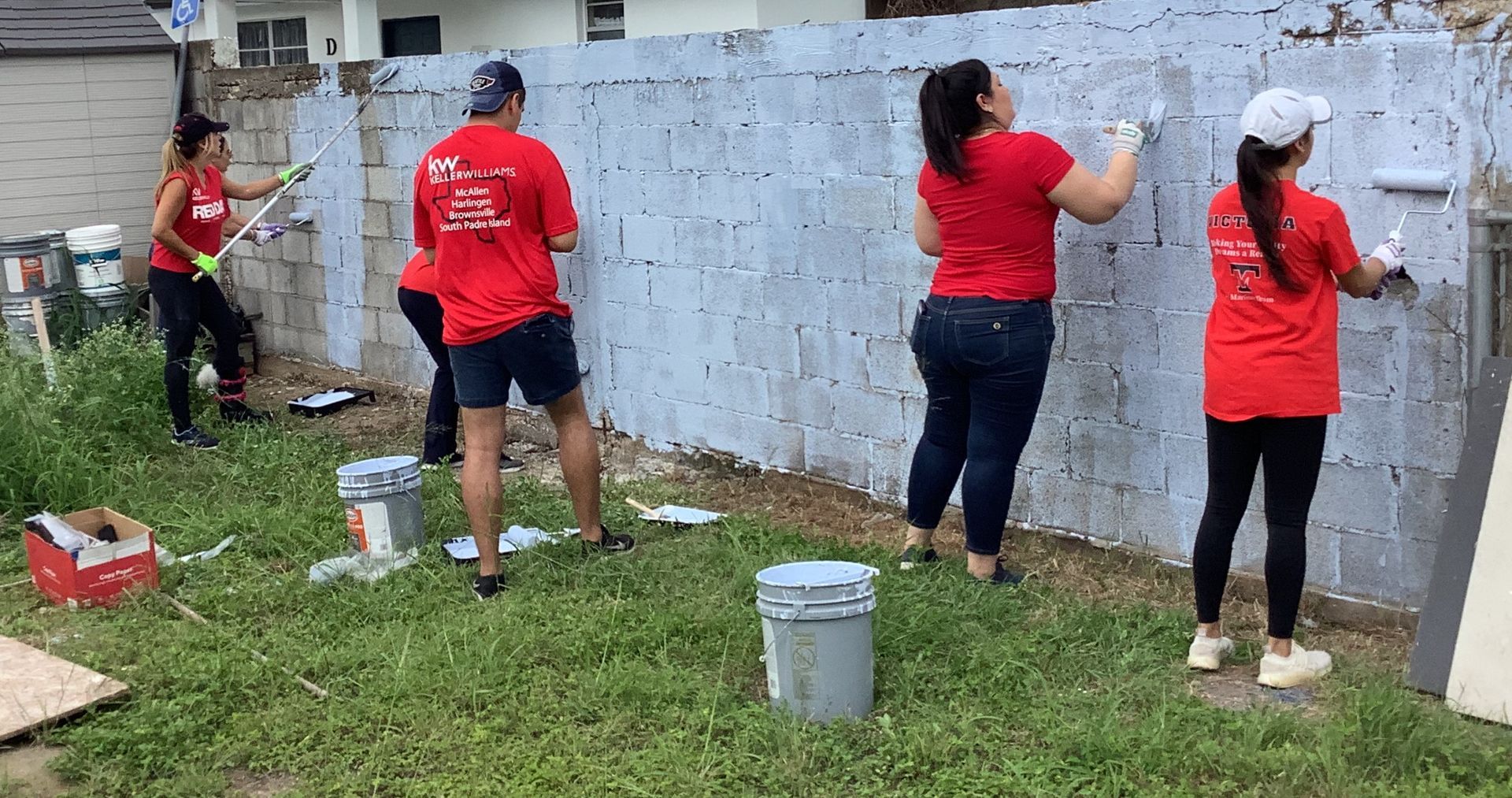 A group of people are painting a brick wall.