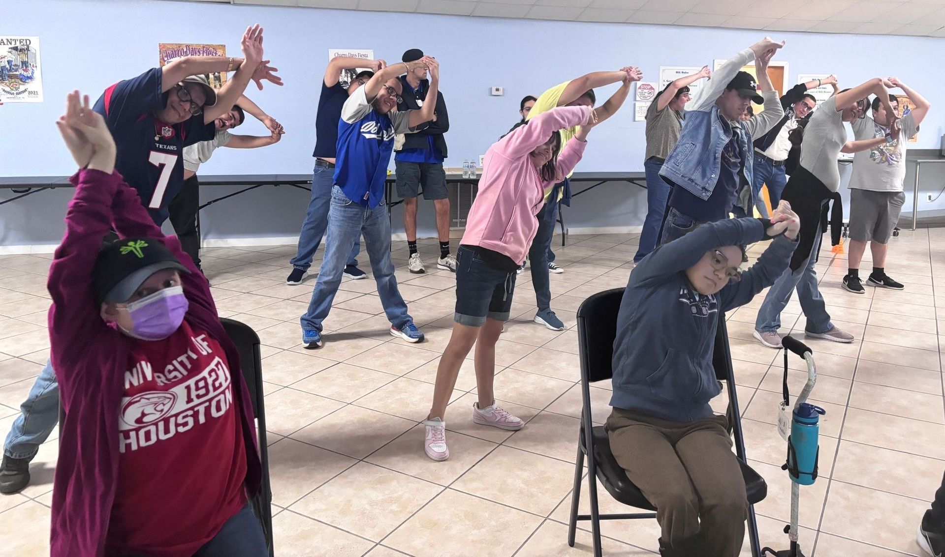 A group of people are stretching their arms in a room.