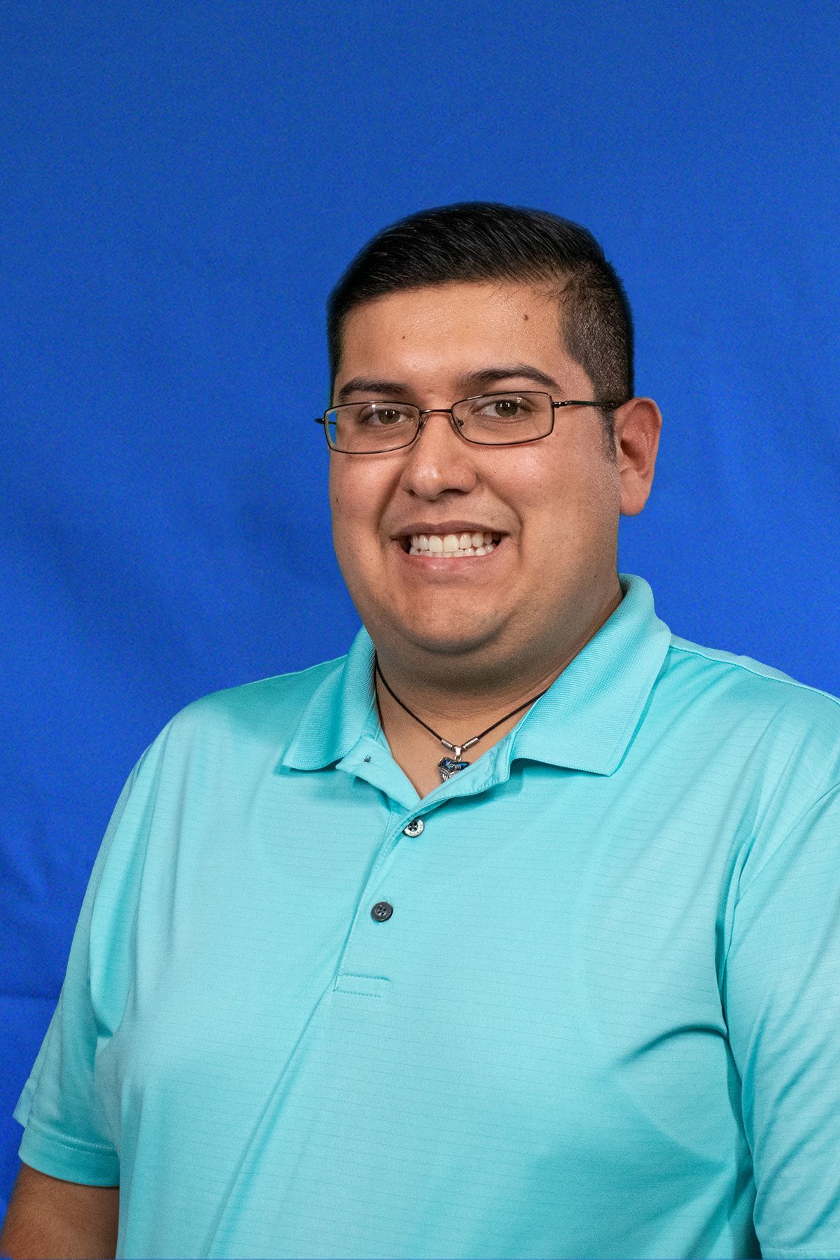 A man wearing glasses and a blue shirt is smiling for the camera.