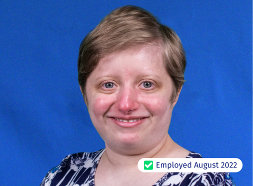A woman is smiling in front of a blue background and has been employed since august 2022