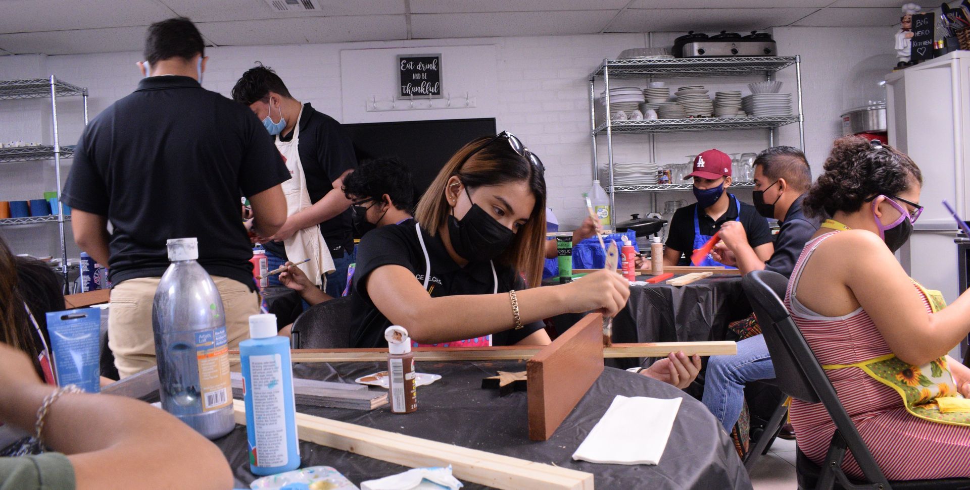 People in workshop wearing masks, building and painting.