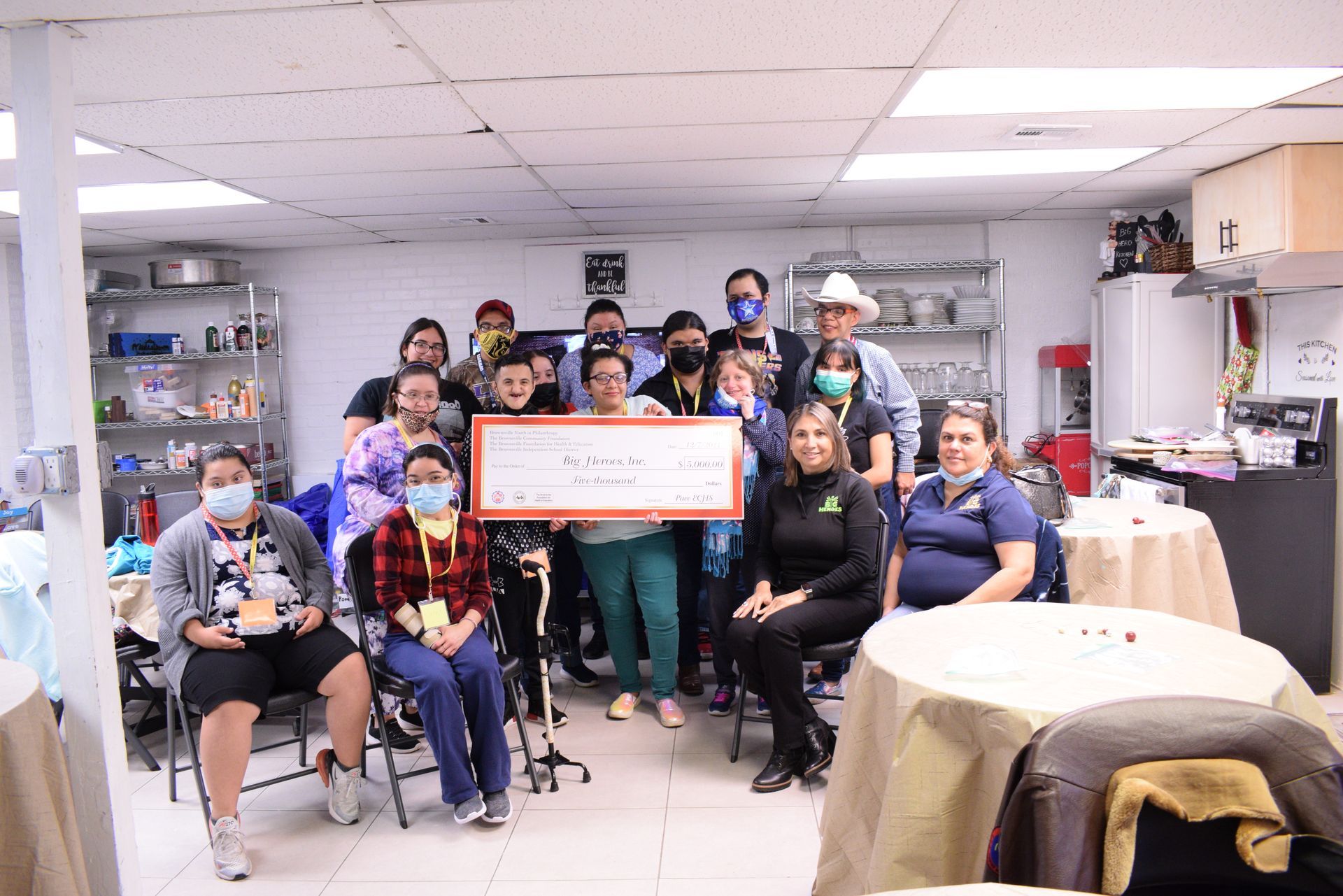 Group of people holding a large check in a room.