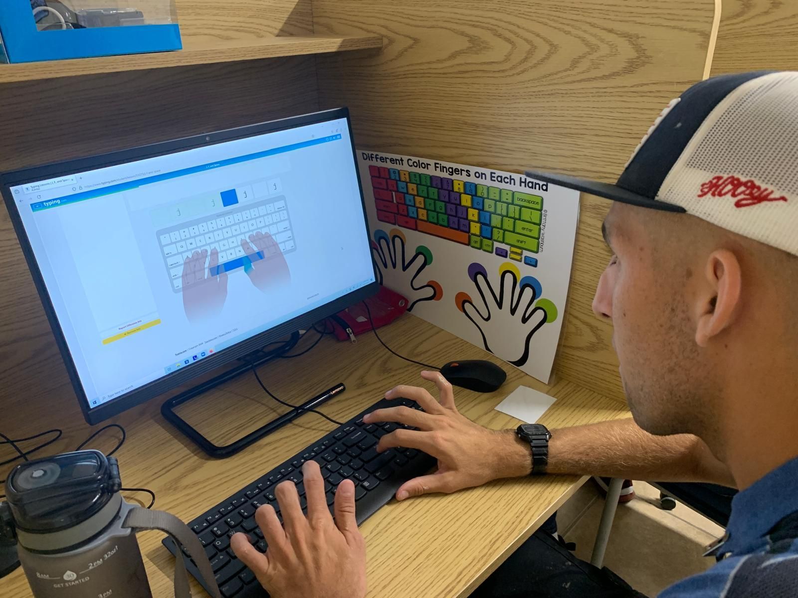 A man in a hat is typing on a computer keyboard.