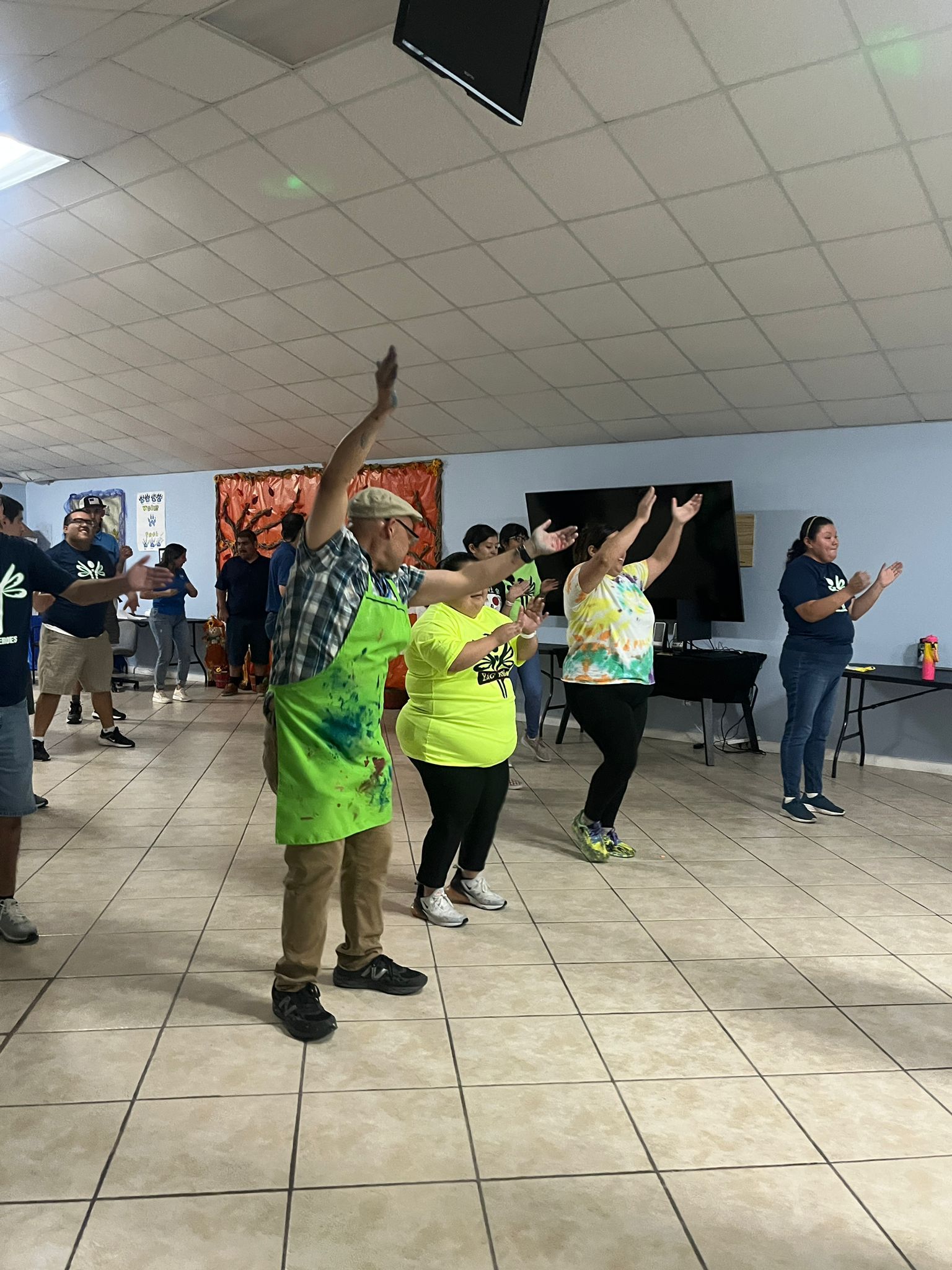 A group of people are dancing in a room with their arms in the air.