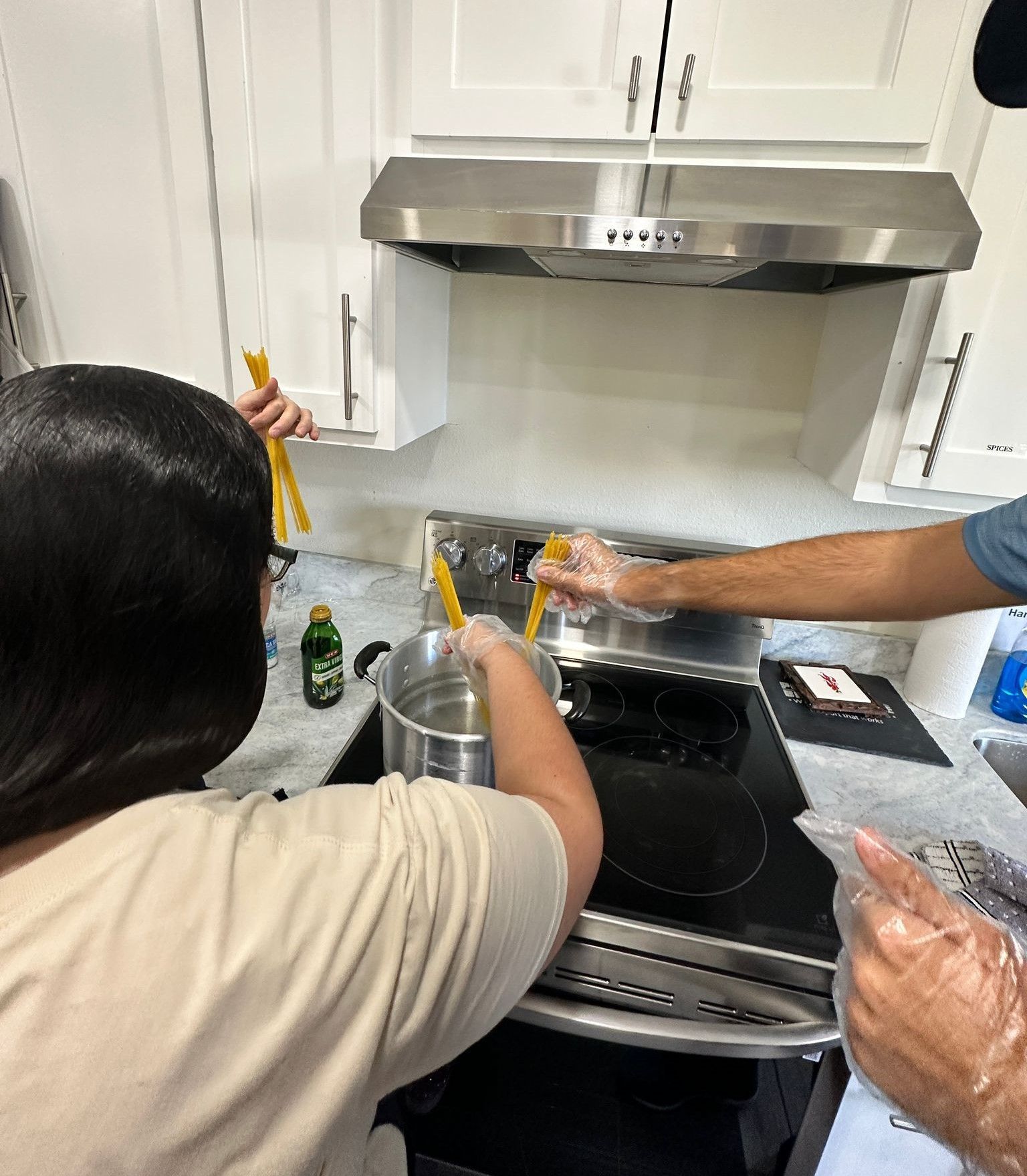 A man and a woman are cooking on a stove in a kitchen.