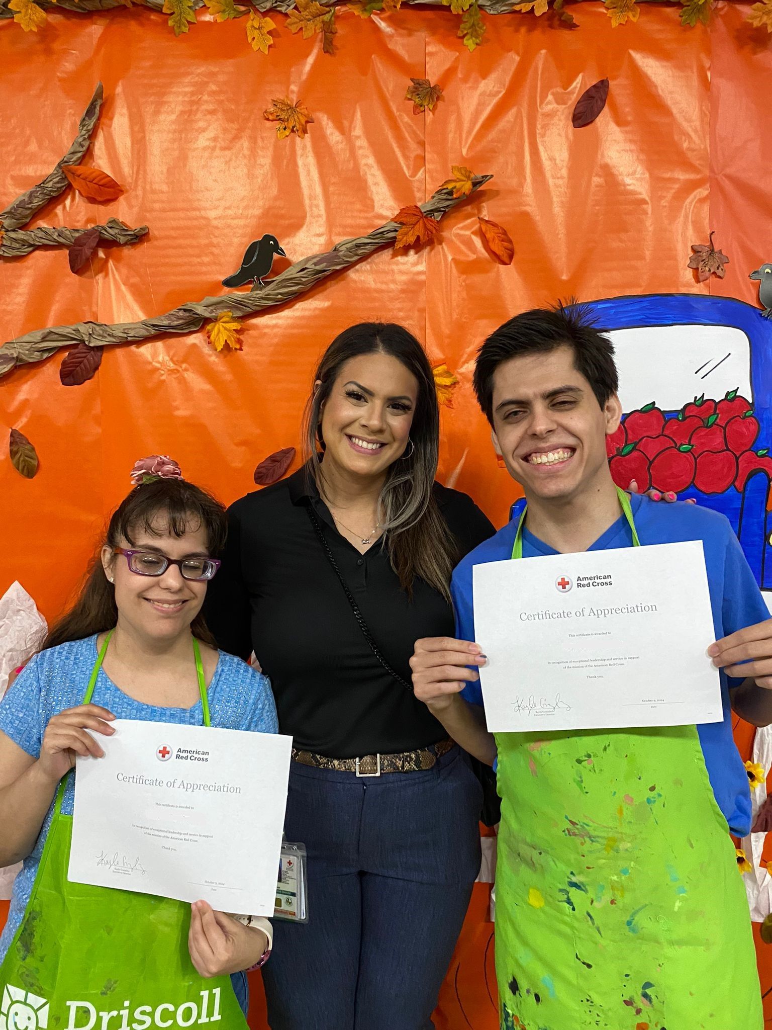 A group of people are standing next to each other holding papers in front of an orange wall.