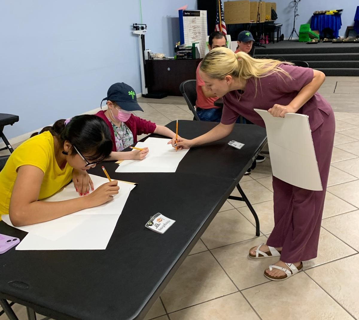 A group of people are sitting at a table writing on paper