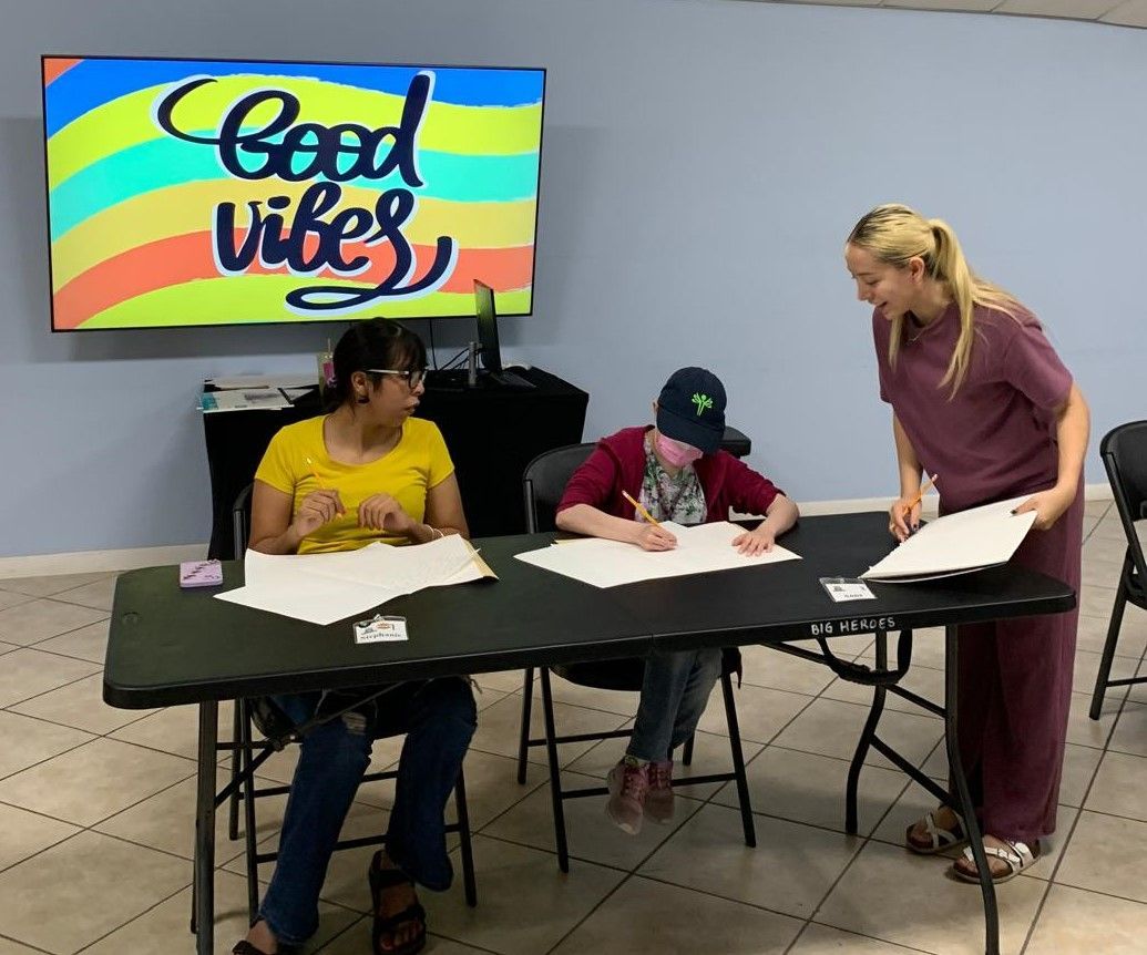 A group of people are sitting at a table in front of a screen that says good vibes