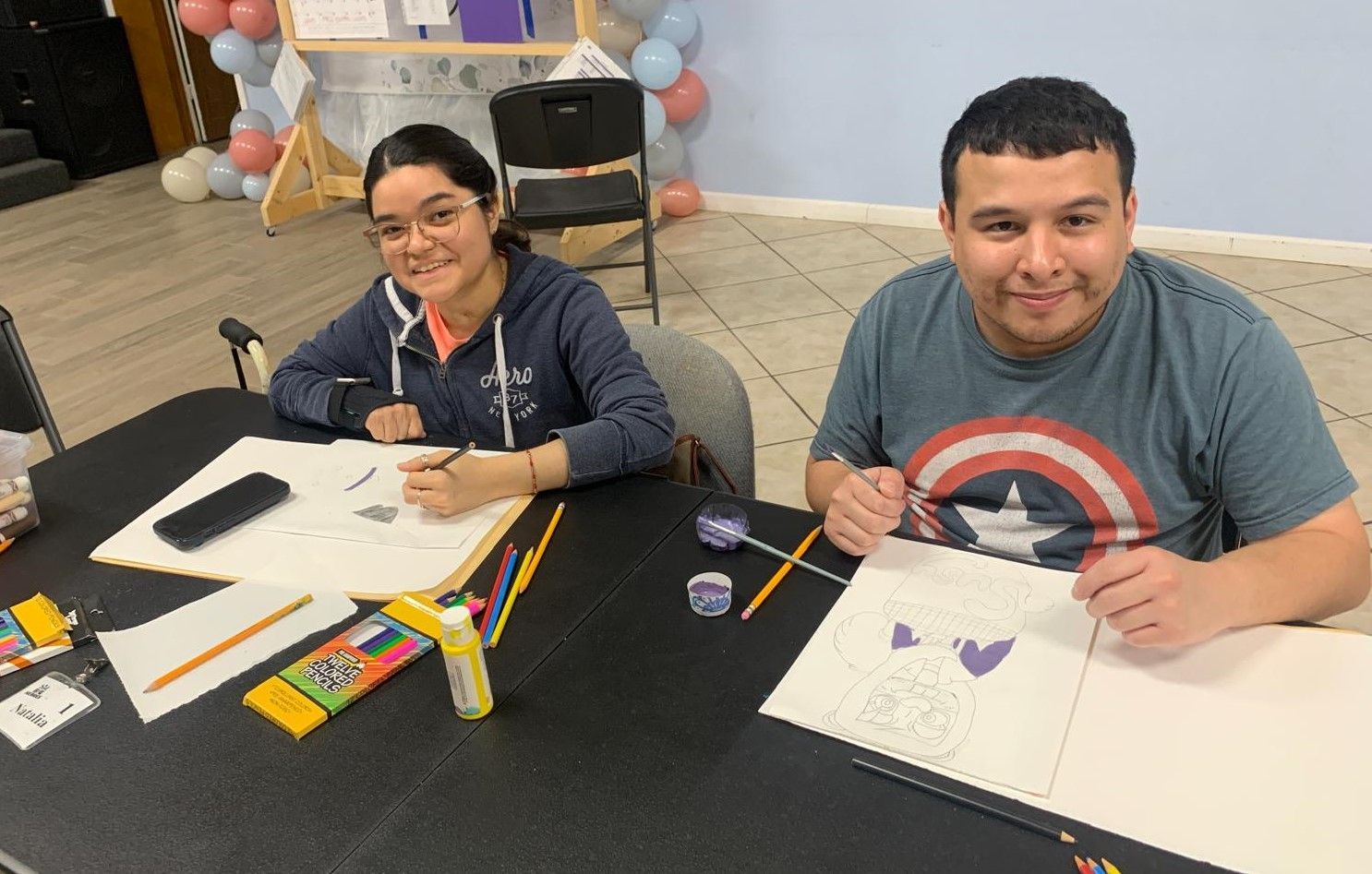 A man and a woman are sitting at a table drawing.